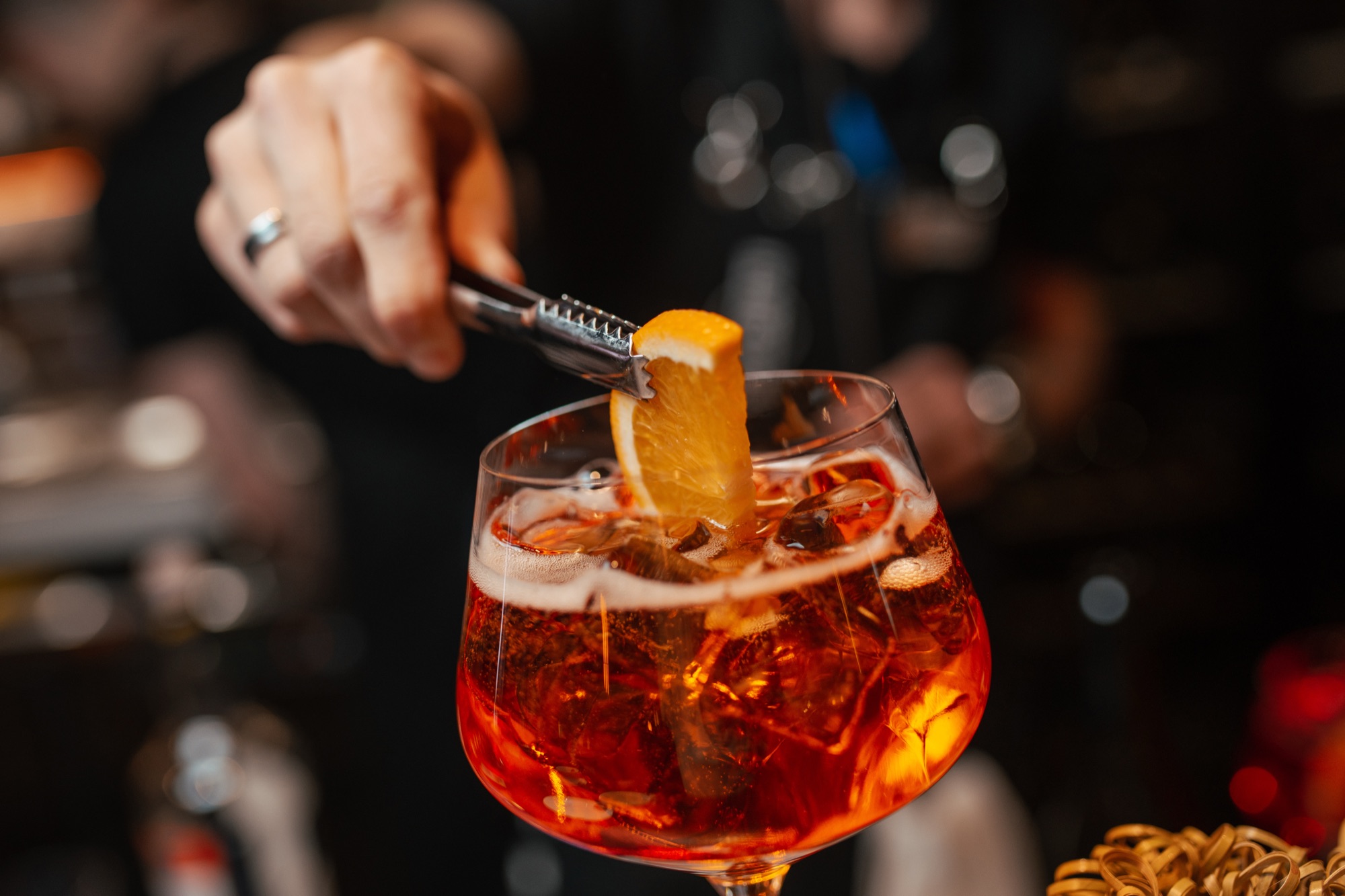 Barkeeper garniert einen Aperitif mit einer Orangenscheibe