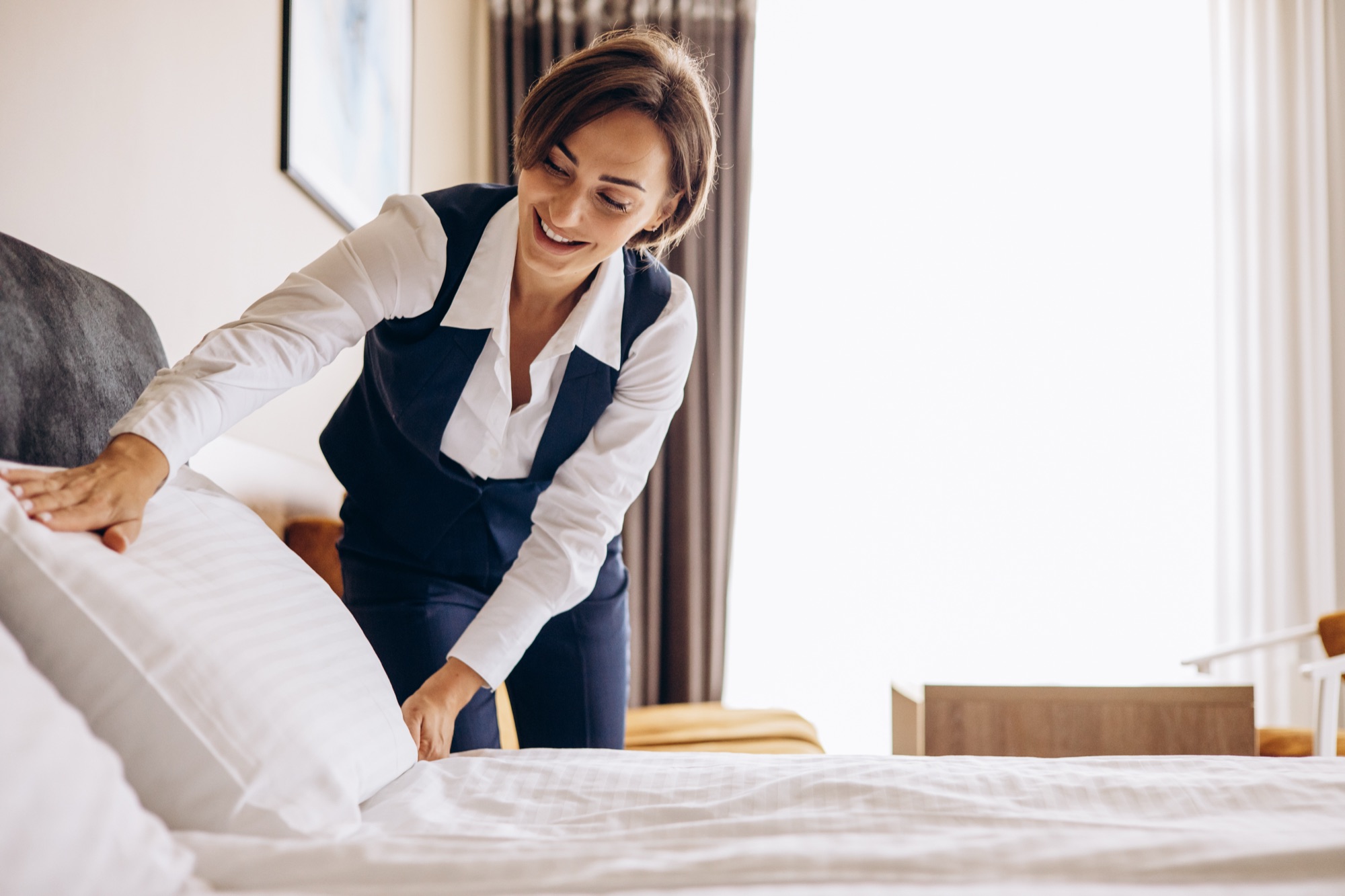 Hotelangestellte macht ein Bett im Hotelzimmer
