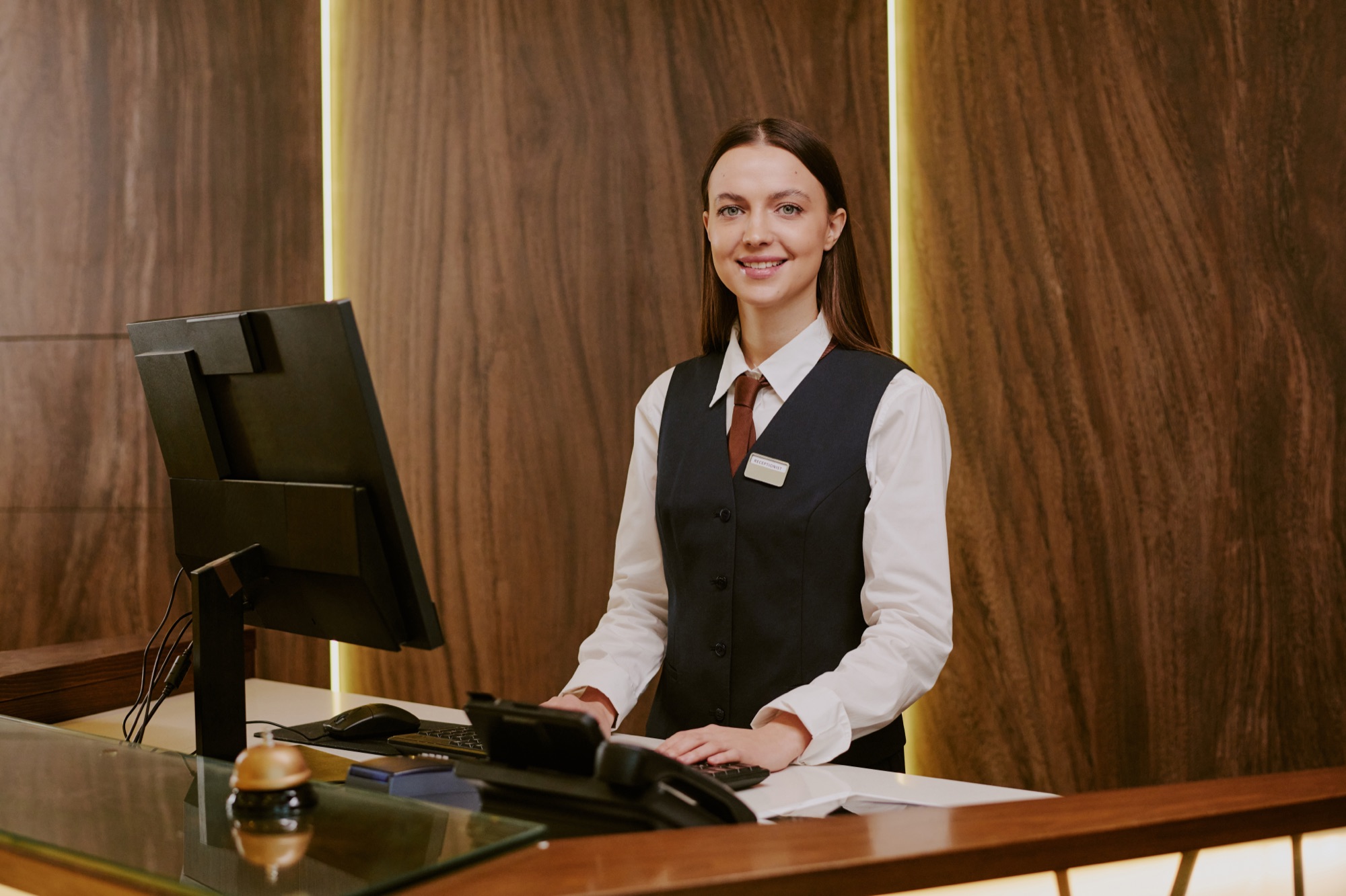 Rezeptionistin steht lächelnd hinter der Hotelrezeption